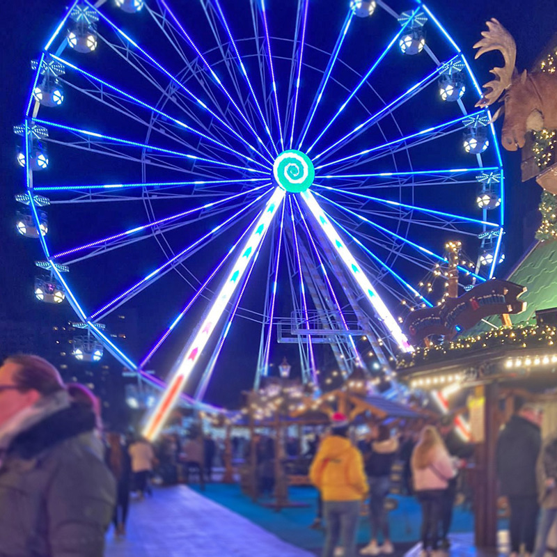 Blau beleuchtetes Riesenrad Northern Eye über den Ständen